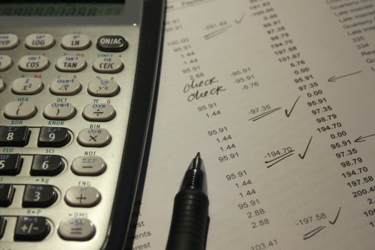 Taschenrechner, Stift und Budgetübersicht auf Zettel